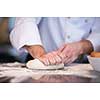 chef hands preparing dough for pizza on table sprinkled with flour closeup