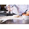 chef hands preparing dough for pizza on table sprinkled with flour closeup