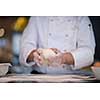 chef hands preparing dough for pizza on table sprinkled with flour closeup