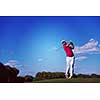 golf player hitting shot with driver on course at beautiful sunny day
