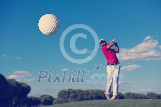 golf player hitting shot with driver on course at beautiful sunny day