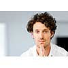 Portrait of a smart young man with curly hair standing in kitchen