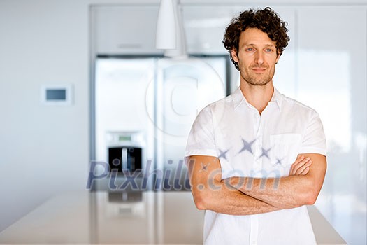 Portrait of a smart young man with curly hair standing in kitchen Portrait of a smart young man with curly hair standing in kitchen