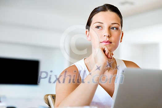Young beautiful woman sitting at the table and working on her laptop Young beautiful woman sitting at the table and working on her laptop