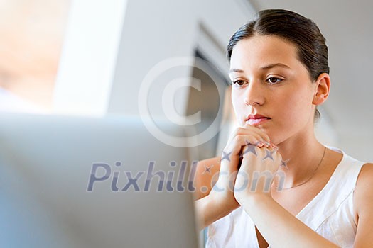 Young beautiful woman sitting at the table and working on her laptop Young beautiful woman sitting at the table and working on her laptop