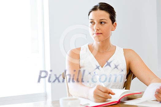 Young woman taking notes at home or office Young woman taking notes at home or office