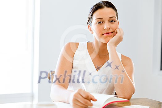 Young woman taking notes at home or office Young woman taking notes at home or office