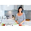 Image of beautiful woman standing in the kitchen and smiling