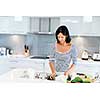 Image of beautiful woman standing in the kitchen and smiling
