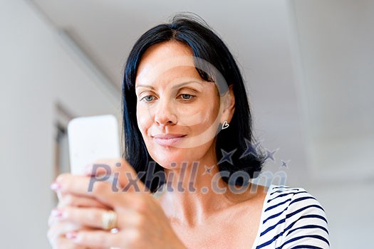 Portrait of attractive woman sitting at desk and holding mobile phone Portrait of attractive woman sitting at desk and holding mobile phone