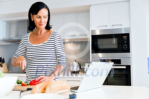 Image of beautiful woman standing in the kitchen and cooking Image of beautiful woman standing in the kitchen and cooking