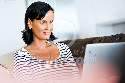 Beautiful woman sitting at home and working on her laptop Beautiful woman sitting at home and working on her laptop