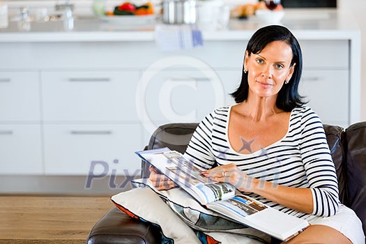 Happy woman reading book sitting on a sofa in the living room at home Happy woman reading book sitting on a sofa in the living room at home