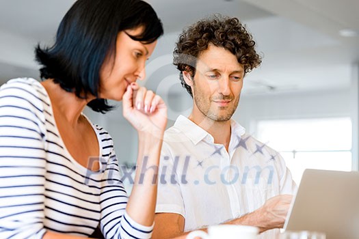 Happy modern couple surfing the net and working on laptop at home Happy modern couple surfing the net and working on laptop at home