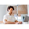 Young man in casual clothes working on laptop at home
