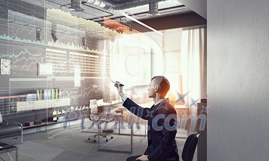 Young businessman sitting in chair and drawing with marker on media screen Young businessman sitting in chair and drawing with marker on media screen
