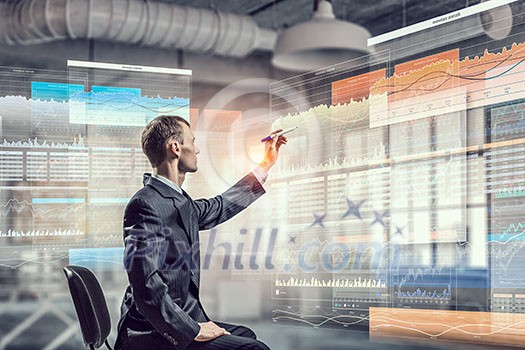 Young businessman sitting in chair and drawing with marker on media screen Young businessman sitting in chair and drawing with marker on media screen