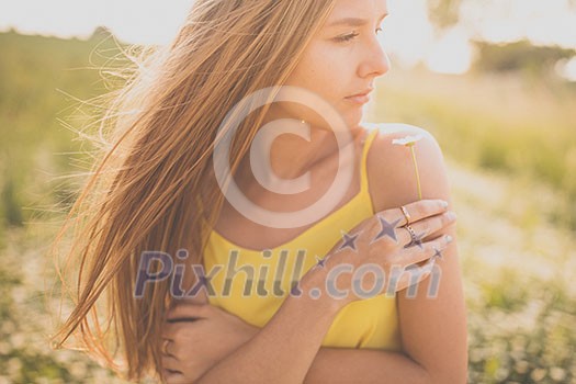 Portrait of young  woman with radiant clean skin lying down amid flowers on a lovely meadow on a spring/summer day