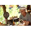 senior man gardener herbalist picking gathering fresh herbs for alternative medicine tea and poutting on balance