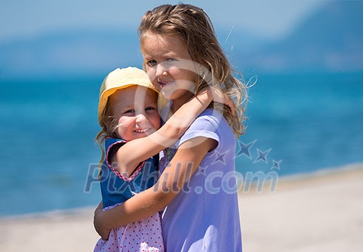 Happy smiling little sisters having fun while hugging on the beach coast during Summer vacation Healthy childhood lifestyle concept Happy smiling little sisters having fun while hugging on the beach coast during Summer vacation Healthy childhood lifestyle concept