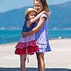Happy smiling little sisters having fun while hugging on the beach coast during Summer vacation  Healthy childhood lifestyle concept