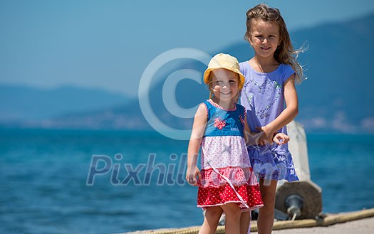 Happy smiling little sisters having fun holding their hands while walking on the beach coast during Summer vacation Healthy childhood lifestyle concept Happy smiling little sisters having fun holding their hands while walking on the beach coast during Summer vacation Healthy childhood lifestyle concept