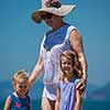 Portrait of a grandmother with her cute little granddaughters holding their hands while standing on the beach coast during Summer vacation
