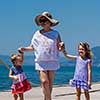 Portrait of a grandmother with her cute little granddaughters holding their hands while standing on the beach coast during Summer vacation