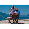 portrait of young happy family with cute little daughters having fun on a bench by the sea during Summer vacation  Healthy family holiday concept