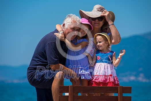 portrait of happy grandparents with cute little granddaughters having fun on a bench by the sea during Summer vacation Healthy family holiday concept portrait of happy grandparents with cute little granddaughters having fun on a bench by the sea during Summer vacation Healthy family holiday concept