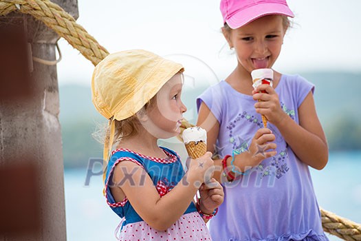 adorable little girls eating ice cream on beach by the sea during Summer vacation adorable little girls eating ice cream on beach by the sea during Summer vacation