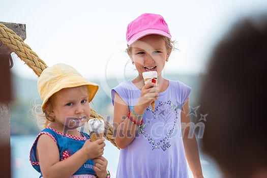 adorable little girls eating ice cream on beach by the sea during Summer vacation