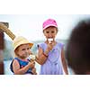 adorable little girls eating ice cream on beach by the sea during Summer vacation