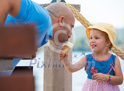 cute little girl having fun with her young father while eating ice cream by the sea during summer vacation holidays, celebration, children and people concept cute little girl having fun with her young father while eating ice cream by the sea during summer vacation holidays, celebration, children and people concept