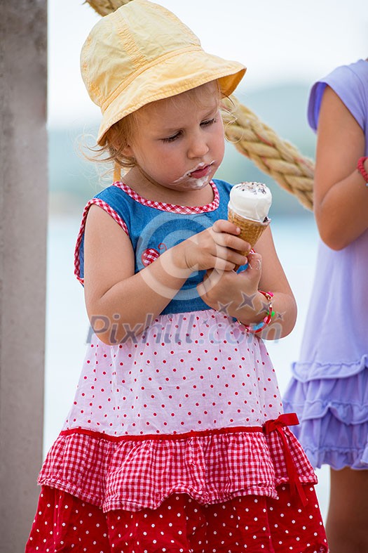 adorable little girls eating ice cream on beach by the sea during Summer vacation adorable little girls eating ice cream on beach by the sea during Summer vacation