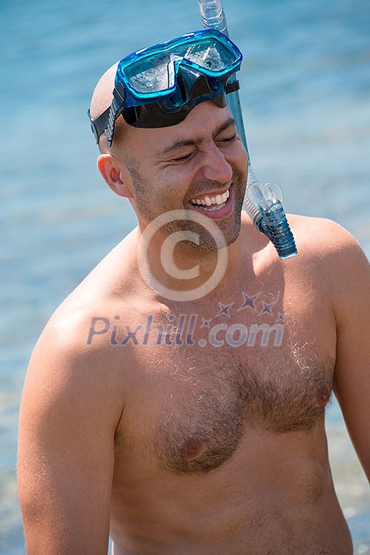 Young smiling fisherman with equipment standing in the shallow water of the sea while preparing for underwater fishing active holiday concept Young smiling fisherman with equipment standing in the shallow water of the sea while preparing for underwater fishing active holiday concept