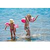 two happy little girls with swimming armbands playing in shallow water of the sea during Summer vacation  Healthy childhood lifestyle concept