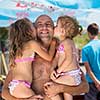 portrait of young happy father having fun with his cute little daughters while holding them in his hands by the sea during Summer vacation  Healthy family holiday concept