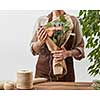 Young girl florist with tattoo hands hold bouquet with fresh flowers roses living coral color in a paper on a gray wall background. Concept floral shop and small business. Mother's Day holiday.