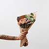 Woman's hand holds beautiful colourful blossoming flower bouquet of fresh roses living coral color on a light background. Place for text. Mother's Day.