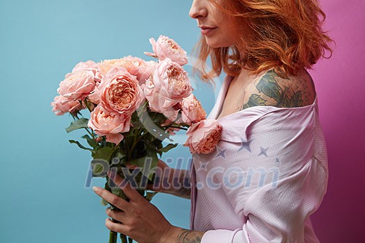 Pretty woman with tattoo holding bouquet of pink bouquet around a double blue pink background with copy space. St. Valentine's Day Pretty woman with tattoo holding bouquet of pink bouquet around a double blue pink background with copy space. St. Valentine's Day