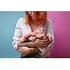 Flowers of pink roses in the hands of a young woman with a tattoo on a double rose against blue background with copy space. Mothers Day