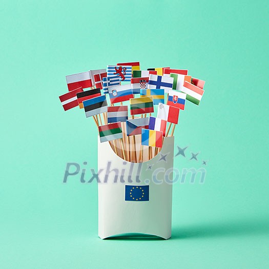 In a cardboard box with sign of the European Union, collection of paper flags of European Union countries on green background . Economic, Political Union of European States In a cardboard box with sign of the European Union, collection of paper flags of European Union countries on green background . Economic, Political Union of European States