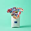 In a cardboard box with sign of the European Union, collection of paper flags of European Union countries on green background . Economic, Political Union of European States
