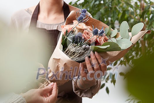 Bouquet of fresh fragrant roses living coral color in a paper with blured green leaf background. Concept of Mother Day. Bouquet of fresh fragrant roses living coral color in a paper with blured green leaf background. Concept of Mother Day.
