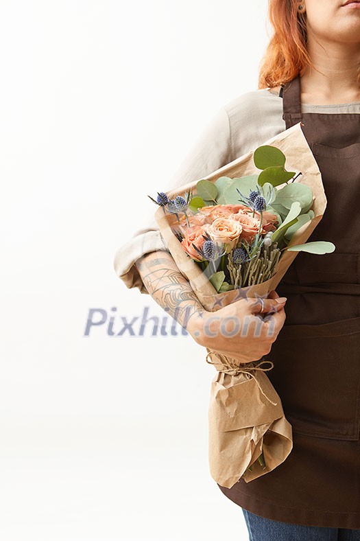 Summer wonderful fresh roses, eryngium and green leaves as a greeting bunch in a female's hand with tattoo on a light background. Place for text. Gift for Mother's or Woman's Day. Summer wonderful fresh roses, eryngium and green leaves as a greeting bunch in a female's hand with tattoo on a light background. Place for text. Gift for Mother's or Woman's Day.