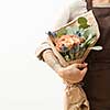 Summer wonderful fresh roses, eryngium and green leaves as a greeting bunch in a female's hand with tattoo on a light background. Place for text. Gift for Mother's or Woman's Day.