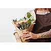 Woman's hands with tattoo are holding beautiful colored living coral rores bouquet. Greeting holiday card for Mother's or Woman's Day. Place for text.
