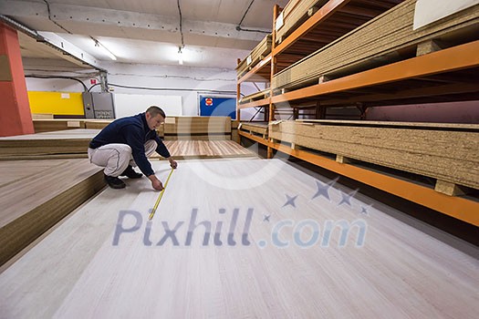 young man carpenter measuring wooden board for cutting while working in big modern carpentry High quality wood concept young man carpenter measuring wooden board for cutting while working in big modern carpentry High quality wood concept