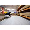 young man carpenter measuring wooden board for cutting while working in big modern carpentry High quality wood concept